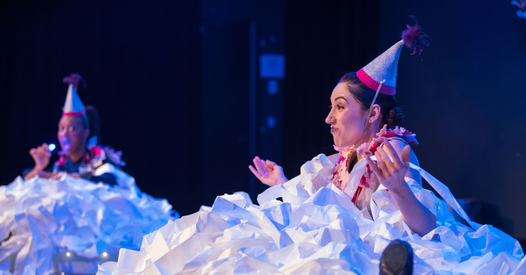 woman with party hat on sitting in a pile of shredded paper