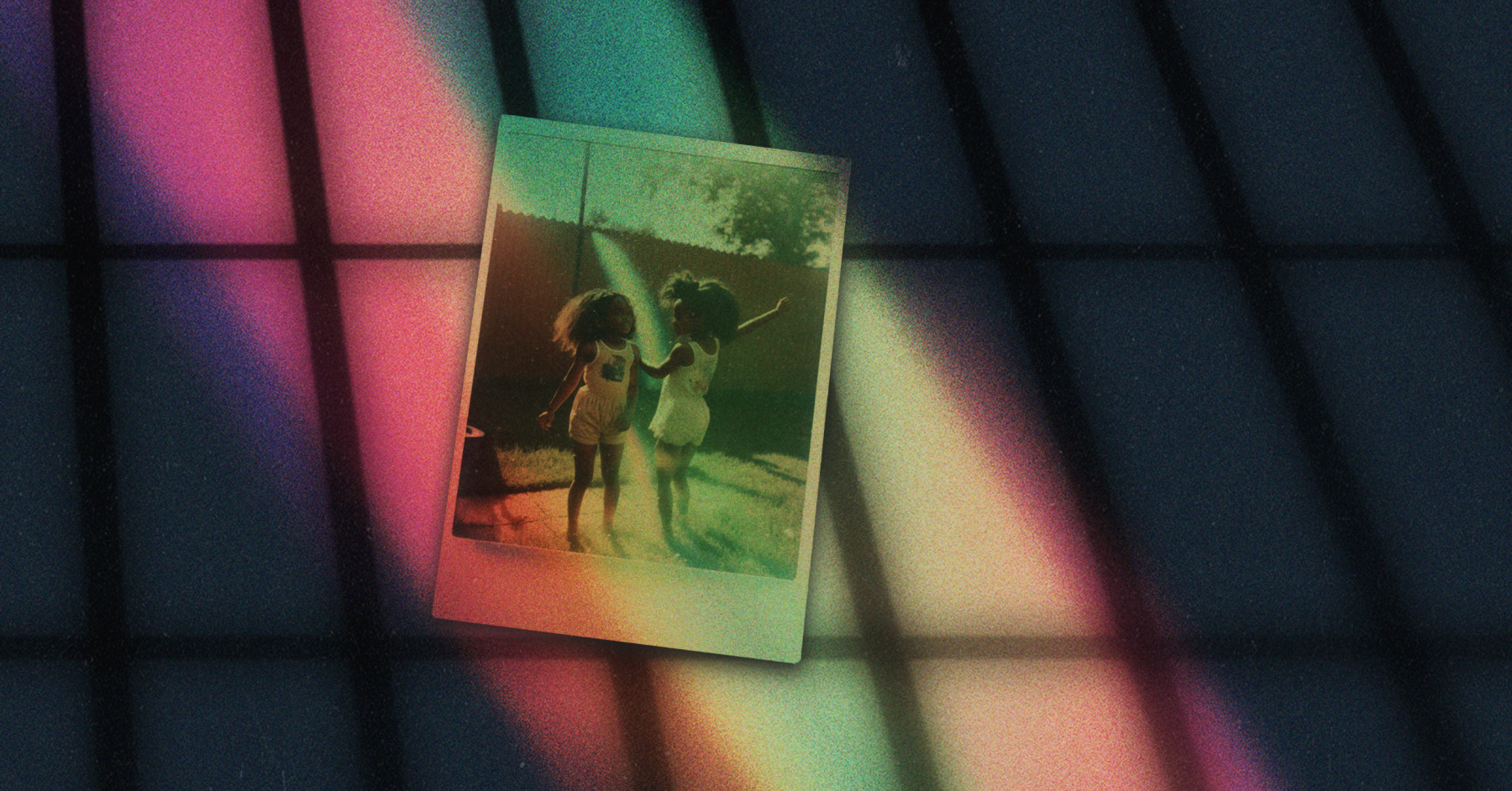 A polaroid photograph of two young Black girls playing in a sprinkler. A shadow of prison bars is cast on the photo and on the background behind with rainbow-colored beam of light.