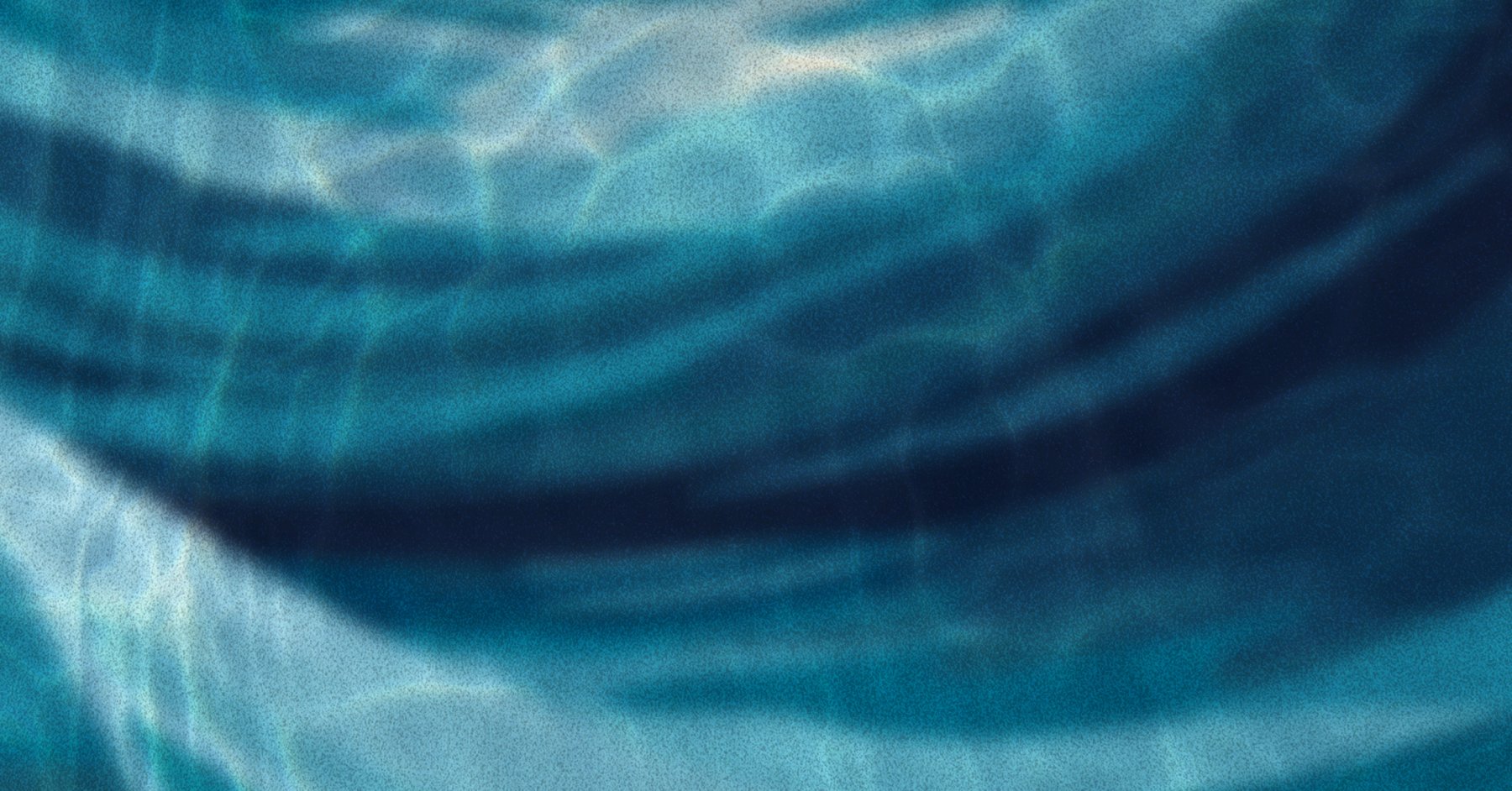 Blue waves under water with light dappling through from above.