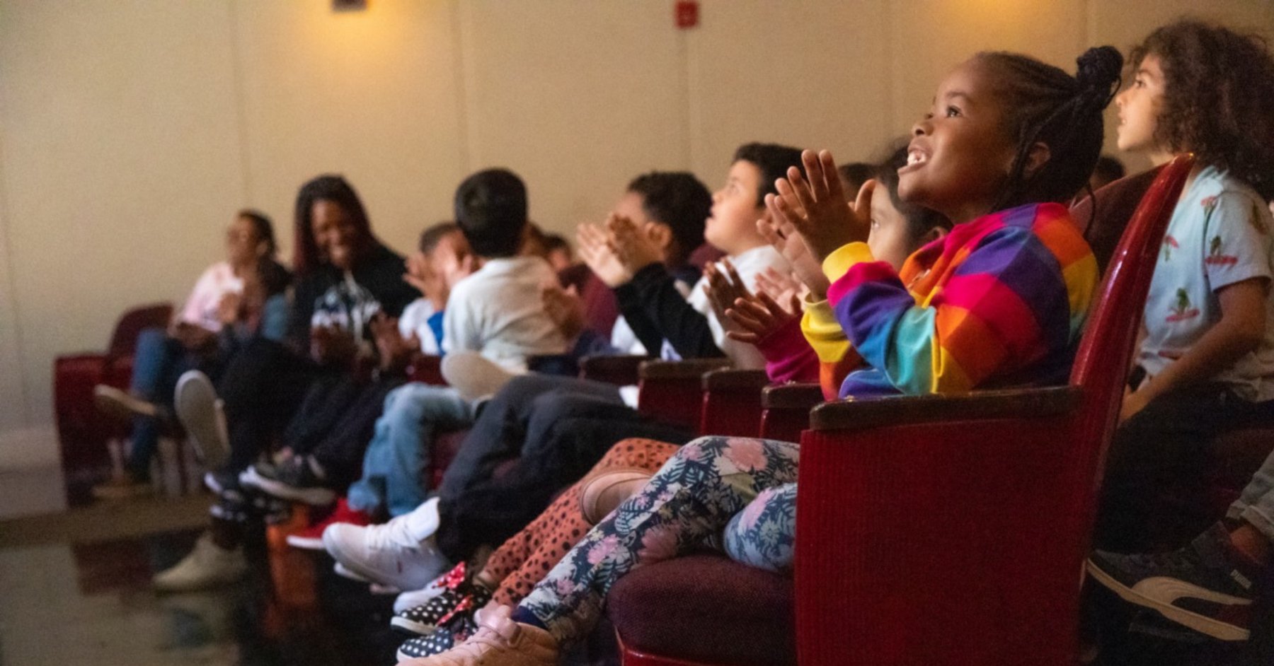 Students seated in a theater, watching a performance.