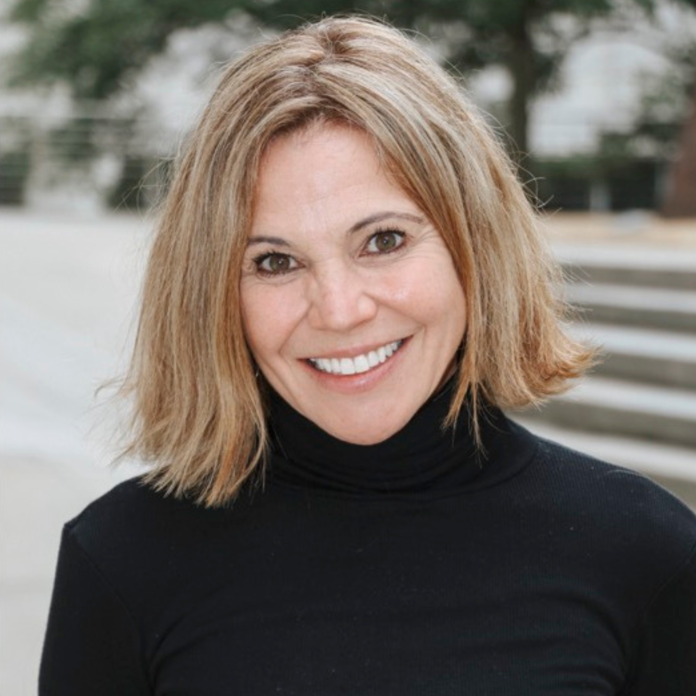 A smiling woman with shoulder-length hair wearing a black turtleneck.