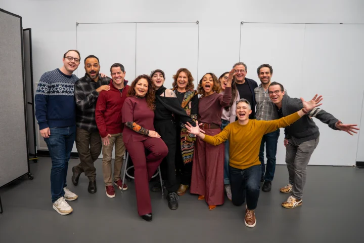 A group of eleven adults stands and kneels together indoors, smiling and posing energetically for a group photo against a plain background, after participating in a Basura clean-up event.