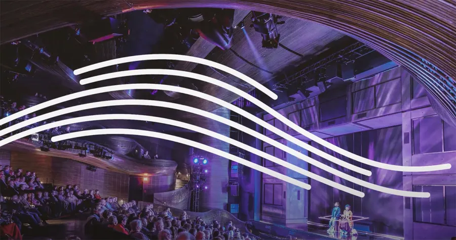 A theater audience watches a stage performance; curved white lines are overlaid across the center of the image.