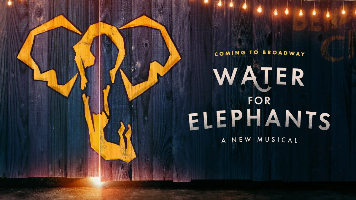 A wooden wall painted with a yellow elephant head outline and text that reads "Water for Elephants: A New Musical, Coming to Broadway.