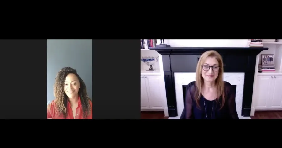 Two women participate in a video call; one sits in front of a plain wall, while the other sits in front of a fireplace and built-in shelves.
