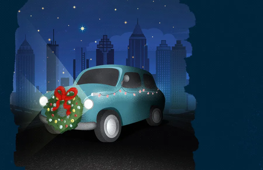 A small blue car decorated with a holiday wreath and string lights is parked at night in front of a city skyline.