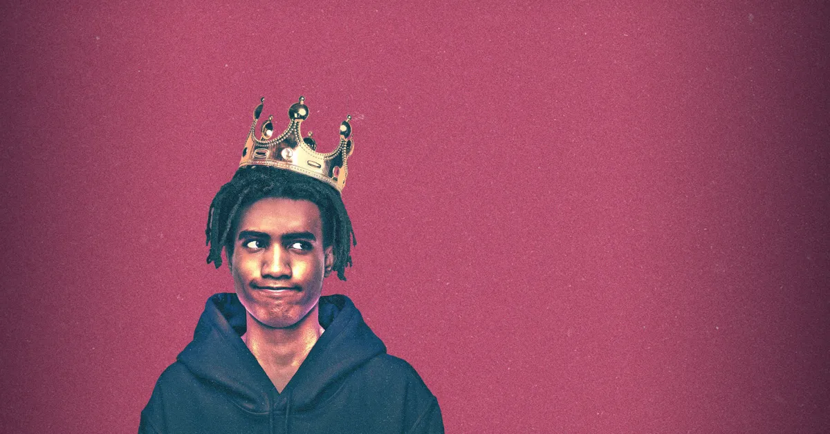 A young person wearing a gold crown and a dark hoodie stands against a textured pink background, looking off to the side with a skeptical expression.