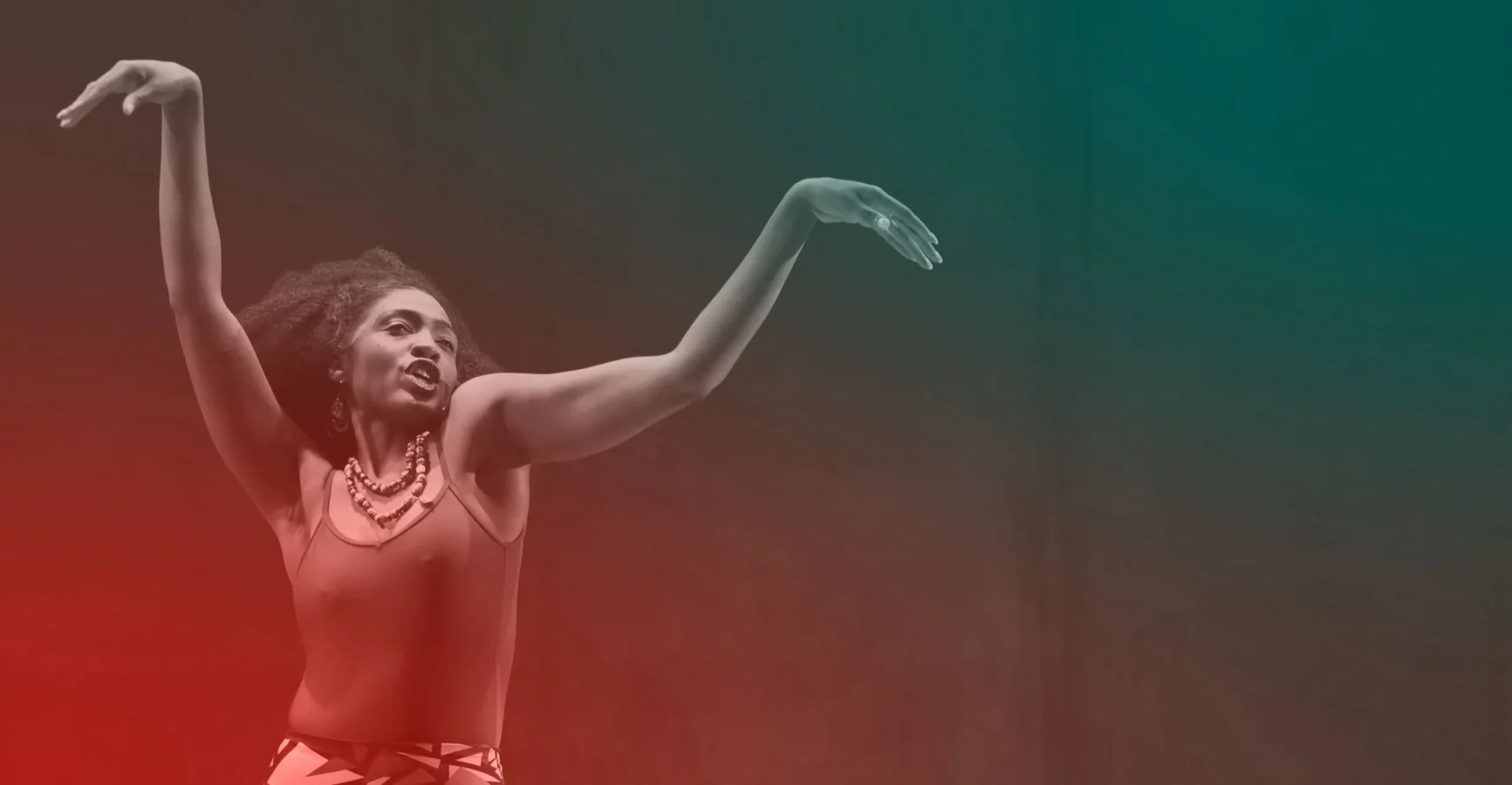 A woman in a sleeveless top and necklace dances with one arm raised and bent, set against a gradient red and green background.