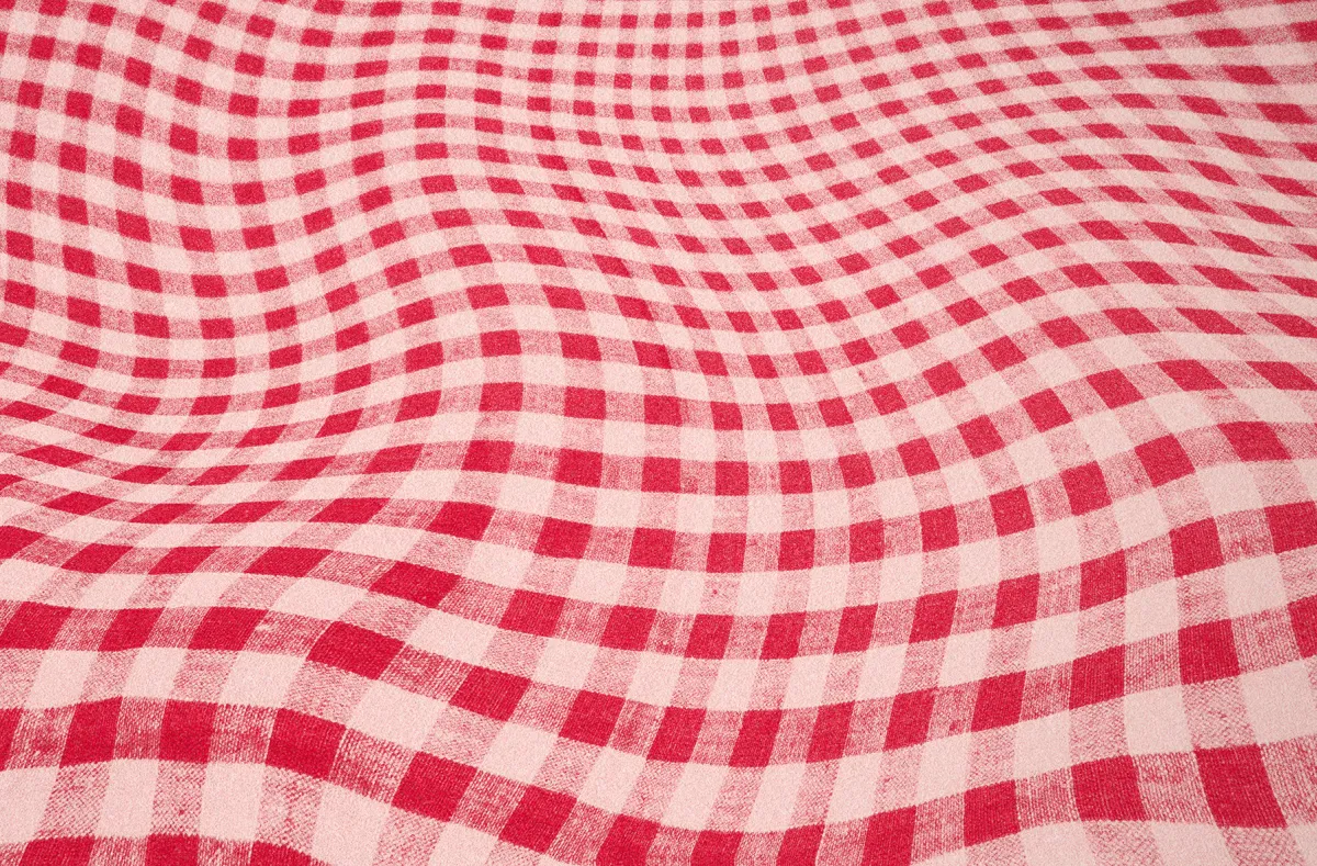 A red and white checkered tablecloth with a distorted, wavy pattern that creates an optical illusion of movement across the surface.