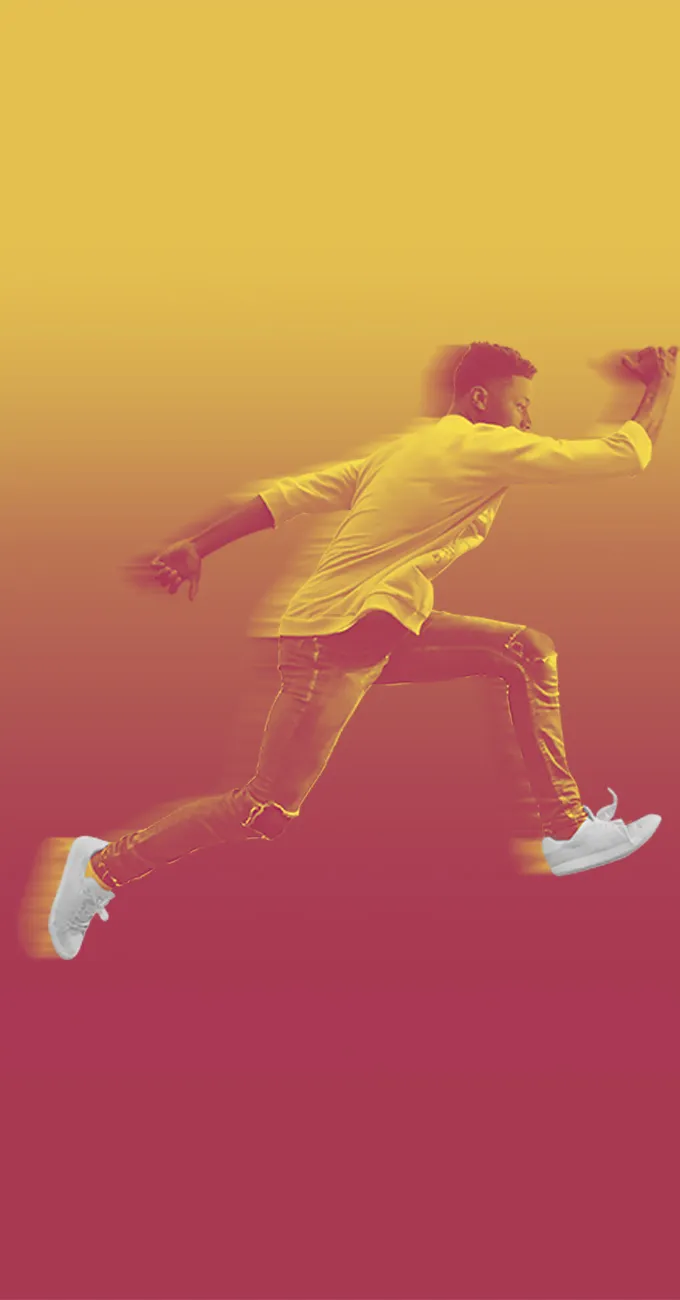 A man in casual clothing and white sneakers is mid-jump against a yellow and red gradient background.