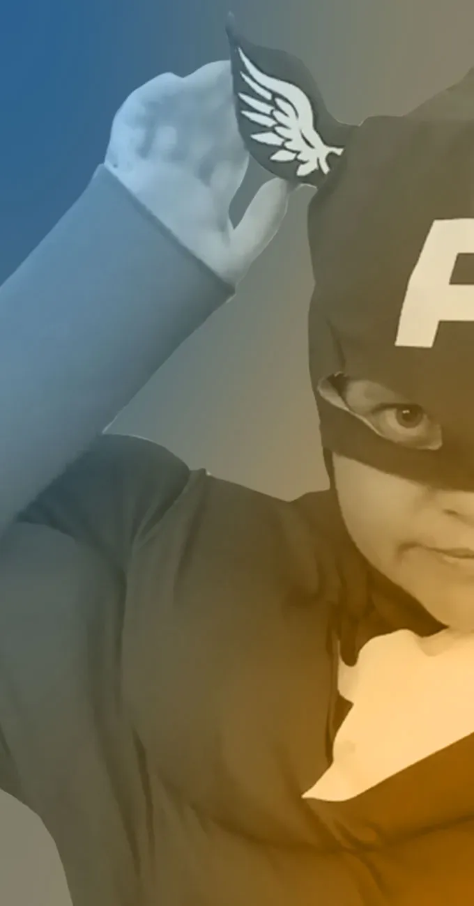 Child in a superhero costume with a winged helmet and mask, adjusting the helmet while looking at the camera.