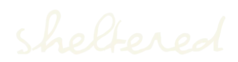 The word "sheltered" is written in a connected, cursive style using a light cream color on a transparent background.