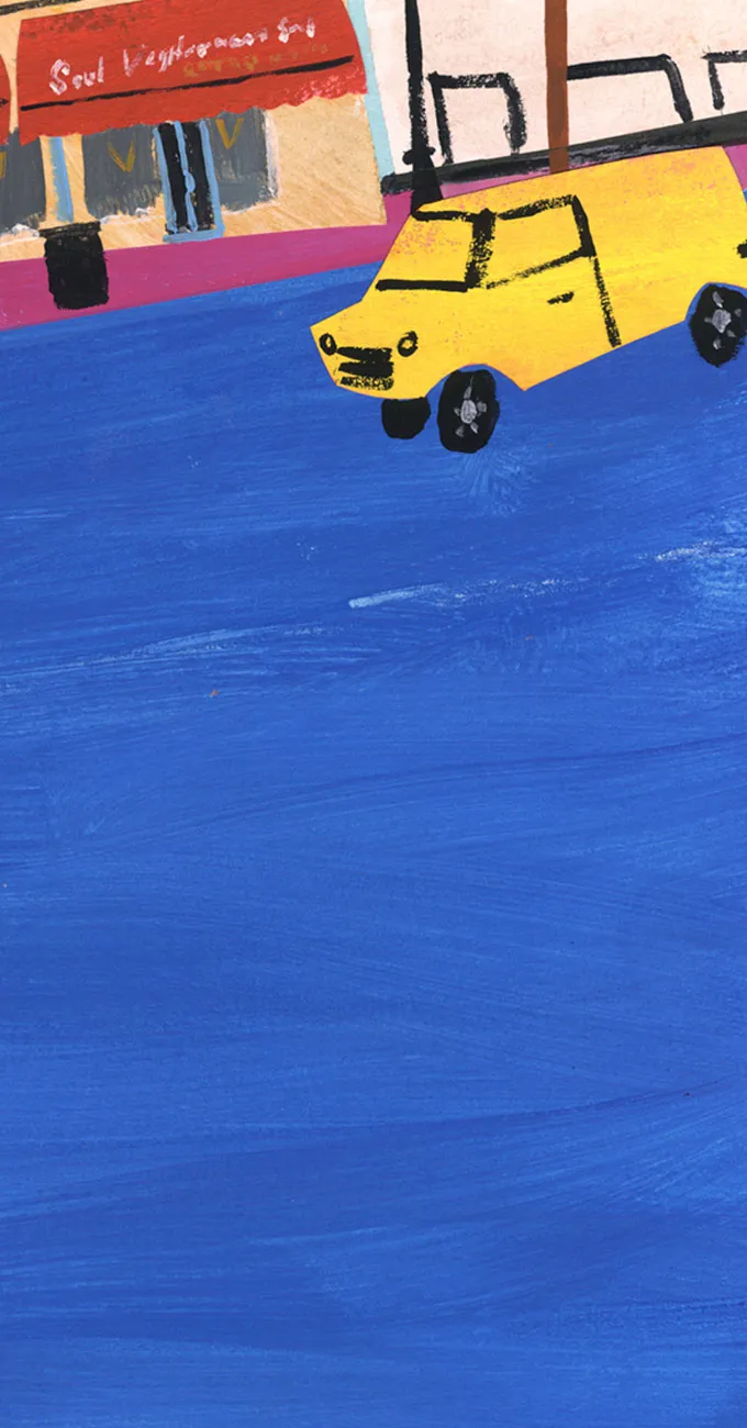 A painted yellow car drives on a blue road near a shop with a red awning that reads "Soul Vegetarian 2.