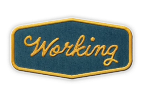 A fabric patch with the word "Working" embroidered in yellow cursive on a blue background, bordered by yellow and gray.