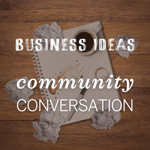 A spiral notebook with coffee stains, a pen, a cup of coffee, and crumpled papers on a wooden desk. Text reads: "Business Ideas, Community, Conversation.