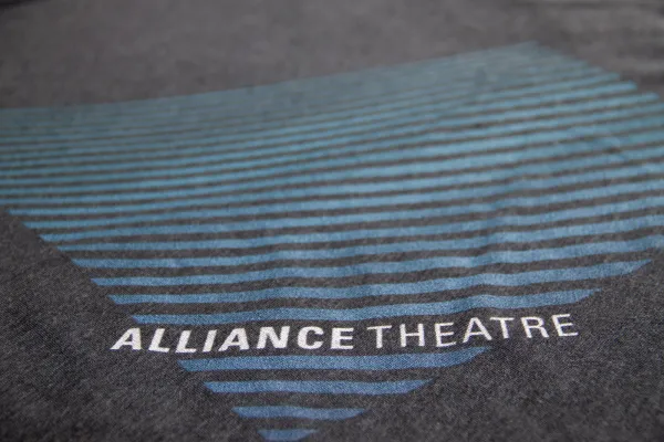 A dark fabric displays the text "ALLIANCE THEATRE" overlaid on a blue, triangular pattern made of horizontal lines.