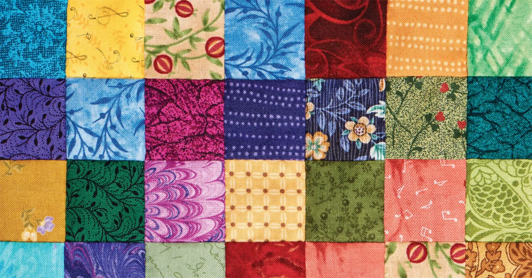 A close-up of a colorful patchwork quilt displaying various fabric squares in different patterns and colors.