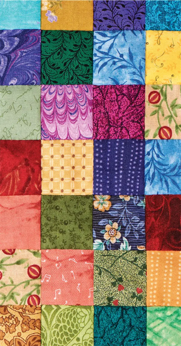 A colorful patchwork quilt made of 24 fabric squares, each with different patterns and colors, arranged in a grid.