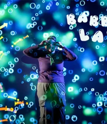 A person stands in front of a colorful, science-themed background with the words "Babble Lab" and various scientific symbols and bubbles.
