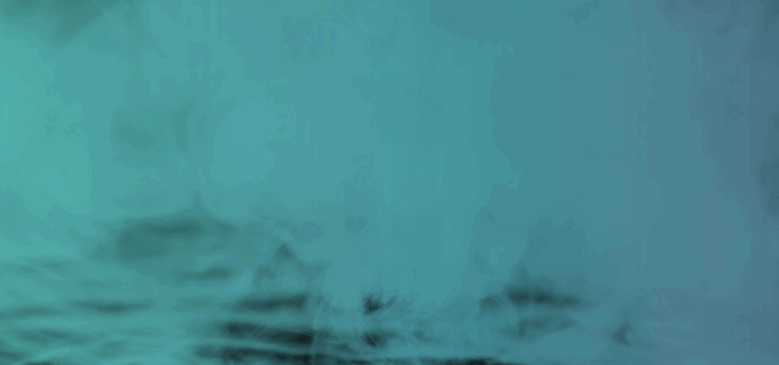 A teal-tinted image showing smoke or mist rising over a dark, blurred surface.