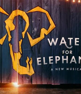 A stylized yellow elephant design on dark wood with the text "Water for Elephants: A New Musical" beside it, illuminated by string lights above.