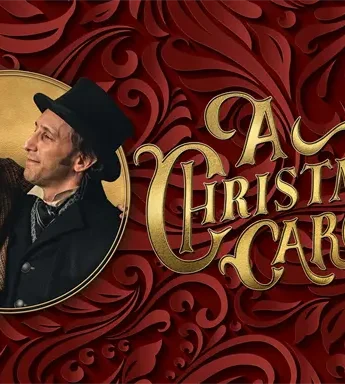 Two men in period clothing smile beside the text "A Christmas Carol" on a red, ornate background.