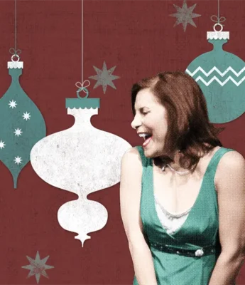 A woman in a green dress laughs in front of a red background decorated with illustrated Christmas ornaments and stars.