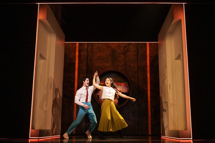 A man and woman dance on stage between two doorways, with warm lighting and a circular design in the background. From the production Maybe Happy Ending on Broadway.