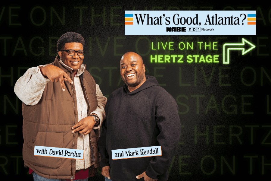 Two men, David Perdue and Mark Kendall, stand smiling in front of a "What's Good, Atlanta? LIVE ON THE HERTZ STAGE" sign with WABE and NPR branding.