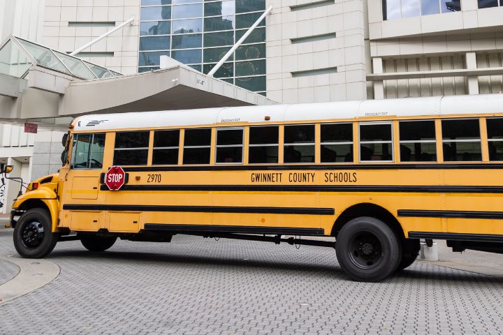 A yellow Gwinnett County Schools bus is parked on a paved area in front of a modern white building.