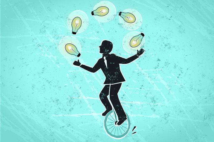 Silhouette of a person in a suit juggling glowing light bulbs while riding a unicycle on a blue textured background.