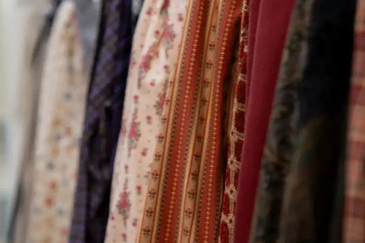 A row of patterned and solid-colored garments on wooden hangers, displayed in a clothing store—reminding us that every Christmas we are different, with new styles and stories to wear each season.
