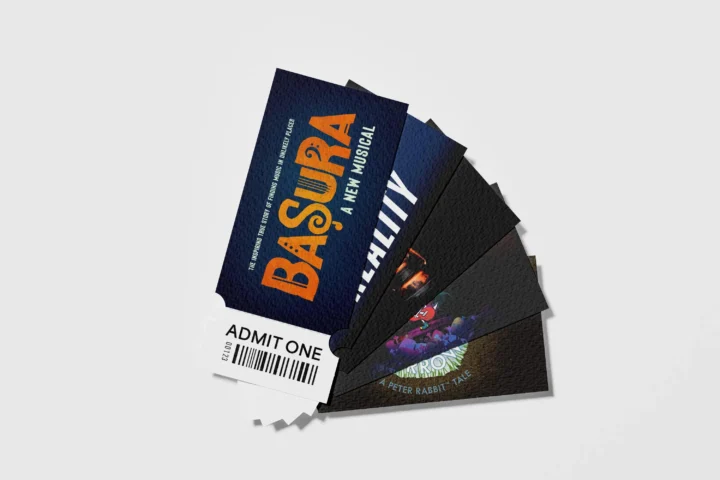 A fan of five event tickets fanned out on a white surface, with the top ticket labeled "Basura: A New Musical" and the bottom showing an "Admit One" stub—the perfect Gift of Theater for any arts enthusiast.