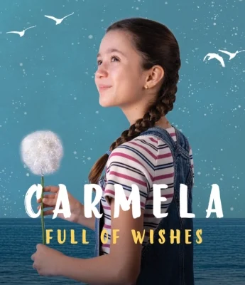 Young girl in a striped shirt and overalls holds a dandelion with purpose against a blue sea and sky, with the text “Carmela Full of Wishes.”.