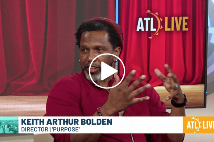 A man in a red shirt and hat gestures while speaking during an interview on ATL LIVE. Text identifies him as Keith Arthur Bolden, director of “Purpose,” passionately discussing the inspiration behind his latest project.