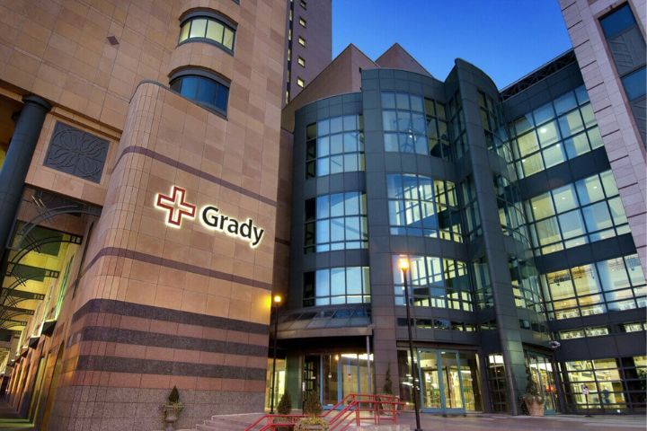 Exterior view of the Grady Hospital building, featuring glass windows and the Grady logo with a red cross on the facade.