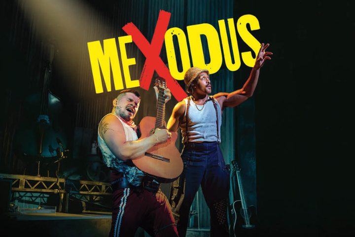 Two performers on stage, one playing guitar and the other gesturing, with the word “MEXODUS” in bold yellow letters above them.